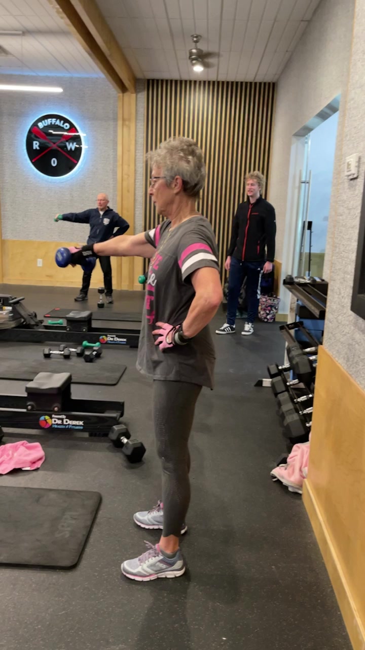 Client doing dumbbell lateral raises with trainer