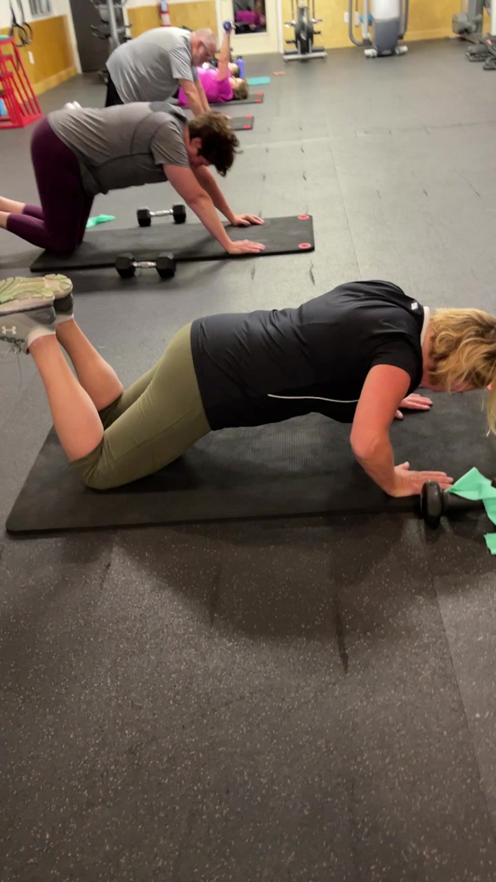 Clients doing modified pushups and floor work with dumbbells