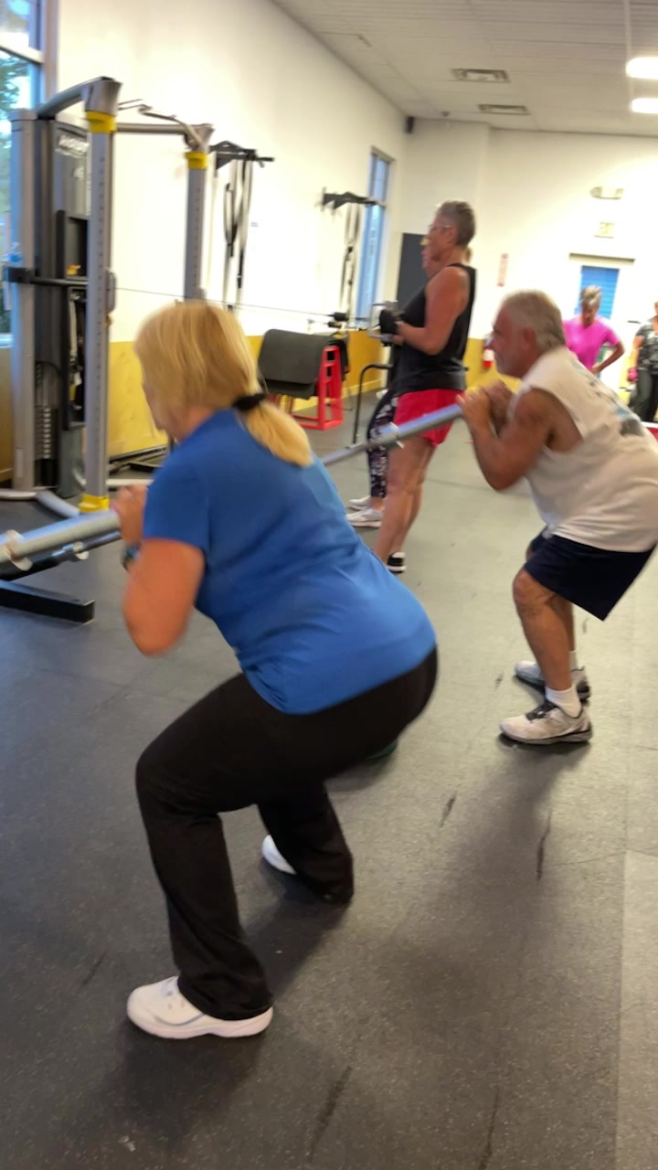 Group of clients doing squats together on gym floor