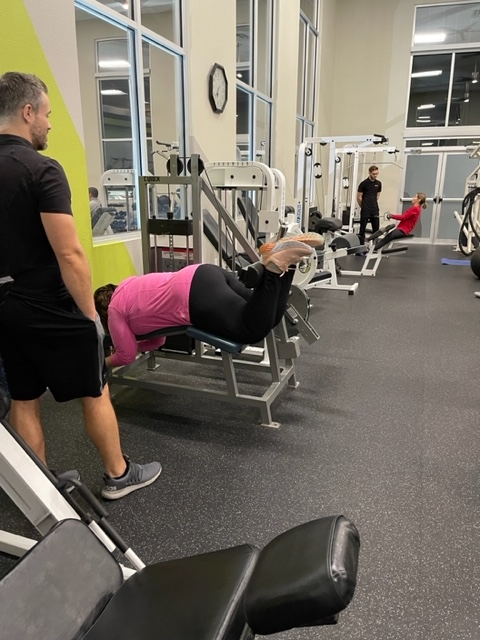 Client on incline machine with trainer spotting