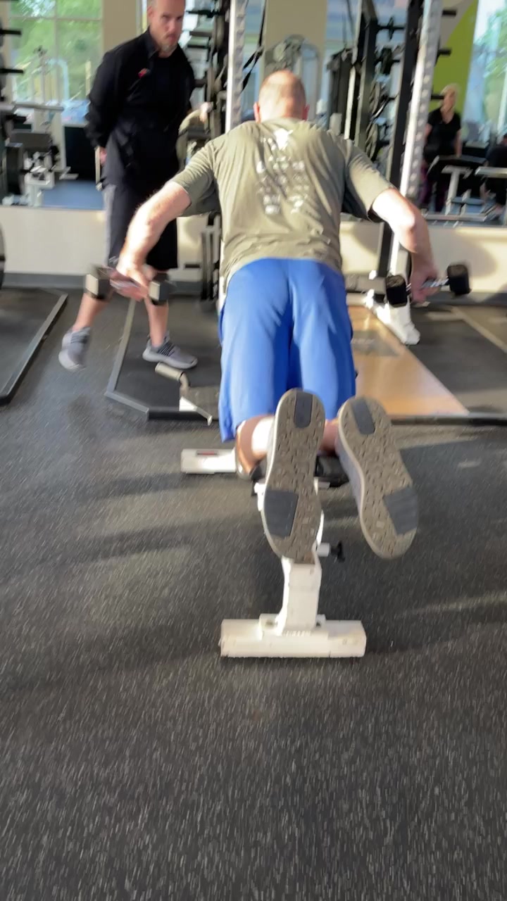 Client doing seated dumbbell curls with trainer
