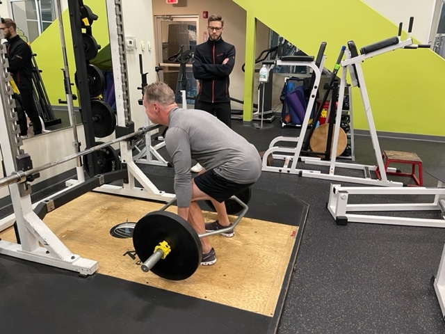 Client performing trap bar deadlifts with trainer watching